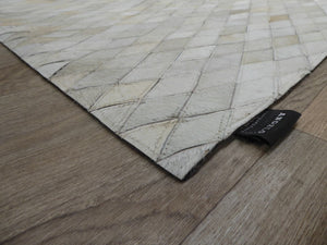 Angle du tapis en cuir de vachette avec motifs géométriques brun gris ivoire, montrant texture et bordures