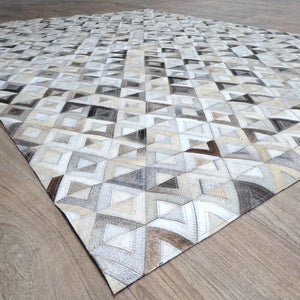 Tapis géométrique en cuir de vachette gris brun ivoire, vu en coin avec perspective du relief