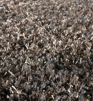 Gros plan sur le tapis à poils longs gris bronze, mettant en valeur la texture soyeuse et les reflets métalliques