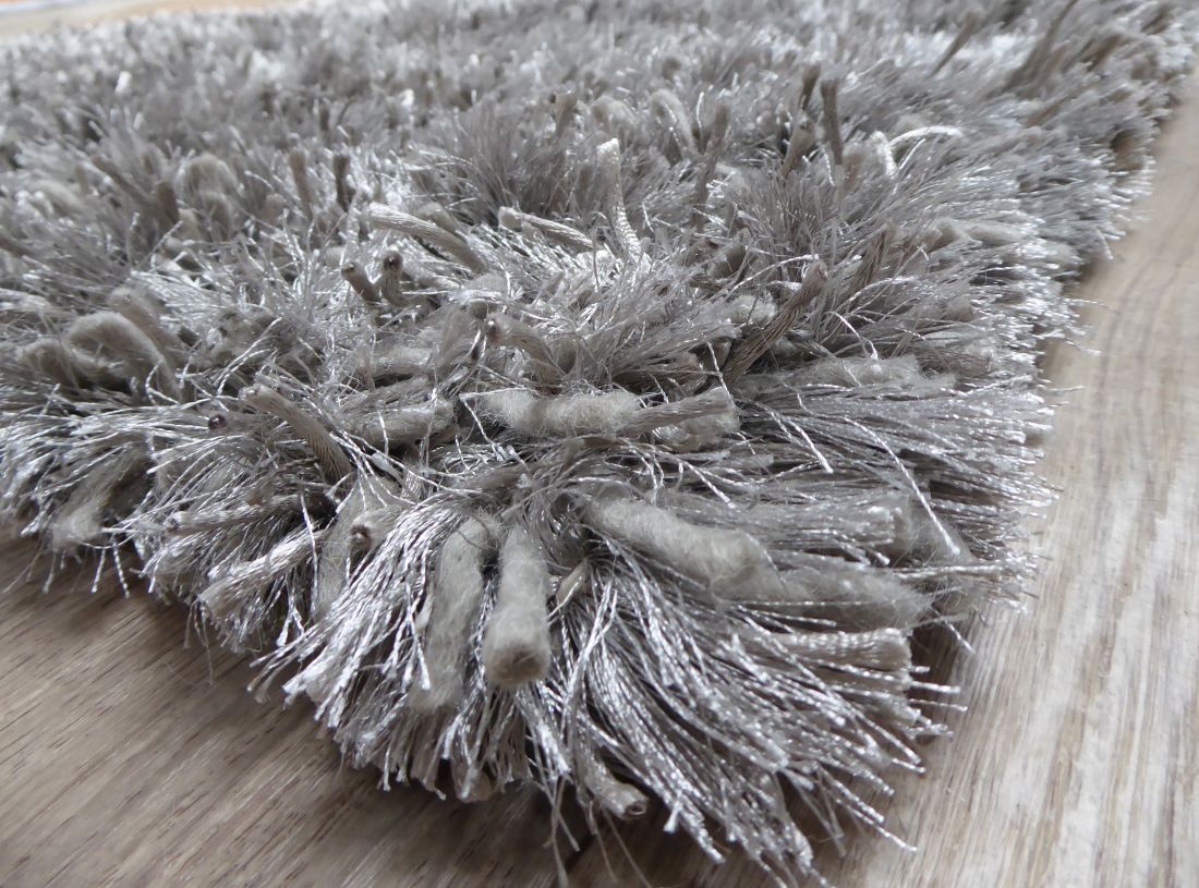 Tapis gris à poils longs photographié en angle, montrant son épaisseur et sa brillance raffinée