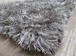 Tapis gris à poils longs photographié en angle, montrant son épaisseur et sa brillance raffinée