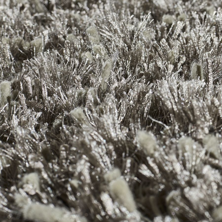 Détail rapproché du tapis gris brillant à poils longs, mettant en valeur la texture soyeuse et la lumière sur les fibres