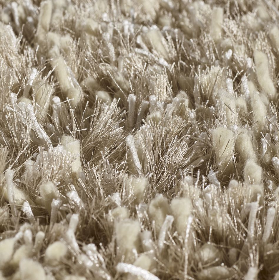 Gros plan sur le tapis à poils longs beige doré, dévoilant la brillance subtile et la qualité des fibres