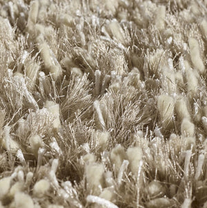 Gros plan sur le tapis à poils longs beige doré, dévoilant la brillance subtile et la qualité des fibres