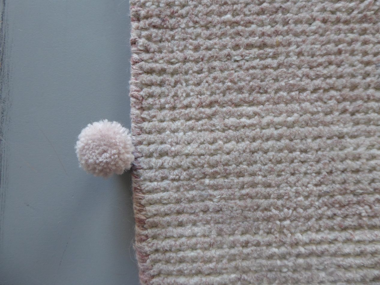 Gros plan sur la texture du tapis vintage beige rose en PET recyclé, montrant les détails de tissage durable