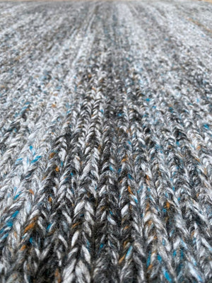 Détail zoomé du tapis en PET recyclé gris bleu orange, texture tissée résistante et écoresponsable