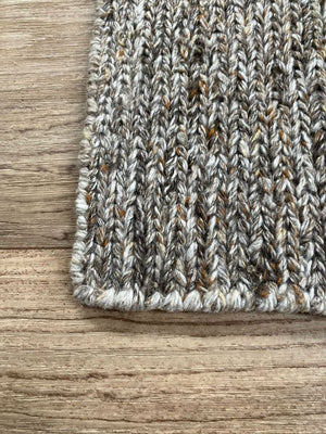 Tapis durable en PET recyclé gris et orange vu de coin montrant le motif du tissage et épaisseur, adapté pour extérieur