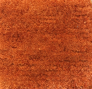 Gros plan sur la texture du tapis en laine orange tissé à la main, mettant en valeur les fibres naturelles et la douceur du tissage