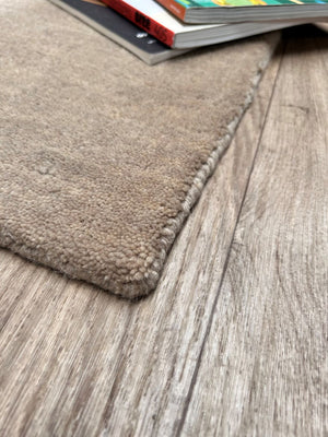 Tapis en laine tissé main couleur sable – vue en angle mettant en valeur les bords finis et la finesse du tissage