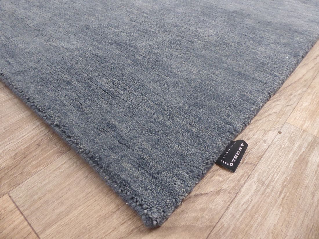 Tapis en laine gris bleu tissé main – photo prise en angle soulignant l’épaisseur et les finitions artisanales