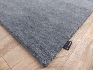 Tapis en laine gris bleu tissé main – photo prise en angle soulignant l’épaisseur et les finitions artisanales