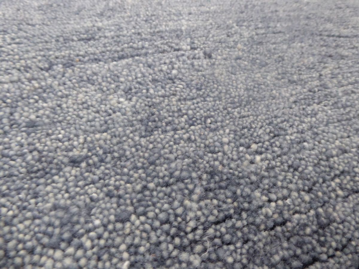 Gros plan sur le tapis gris bleu en laine tissé main – détails du tissage artisanal et de la texture soyeuse