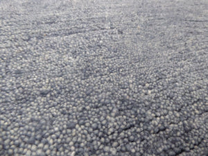 Gros plan sur le tapis gris bleu en laine tissé main – détails du tissage artisanal et de la texture soyeuse