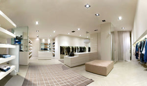 Tapis design taupe aux formes irrégulières, mis en scène dans une boutique contemporaine, apportant chaleur et élégance