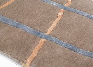 Bord du tapis design en laine et viscose taupe aux détails colorés, montrant l’épaisseur et la texture des fibres