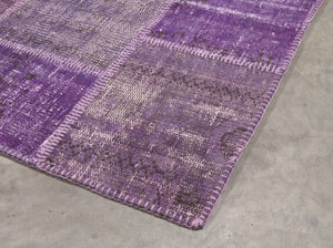 Tapis patchwork recyclé violet laine et coton, photographié en angle, mettant en valeur la texture et le relief