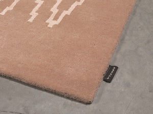Détail du tapis laine–viscose rose pâle en angle, montrant la texture et le motif zigzag en perspective