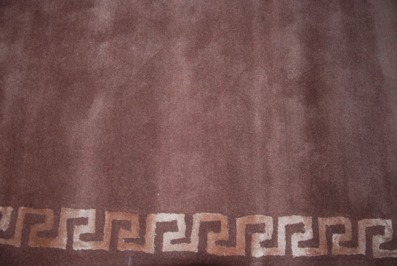 Gros plan sur la texture du tapis motifs grecs en viscose et laine, tons bronze et marron
