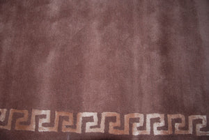 Gros plan sur la texture du tapis motifs grecs en viscose et laine, tons bronze et marron