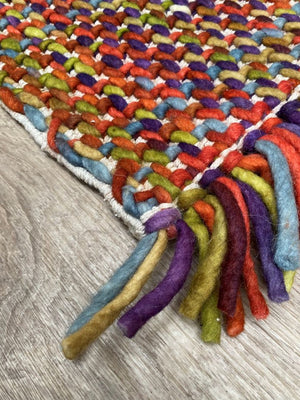 Tapis en laine aux couleurs vives, texture tweed-tartan et franges épaisses, photographié en angle