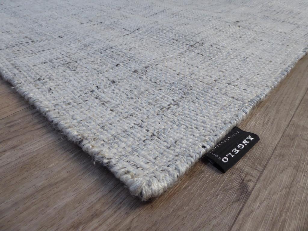 Tapis blanc gris artisanal en laine et viscose – vue en angle soulignant l’épaisseur et les finitions soignées