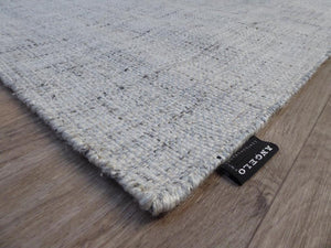 Tapis blanc gris artisanal en laine et viscose – vue en angle soulignant l’épaisseur et les finitions soignées