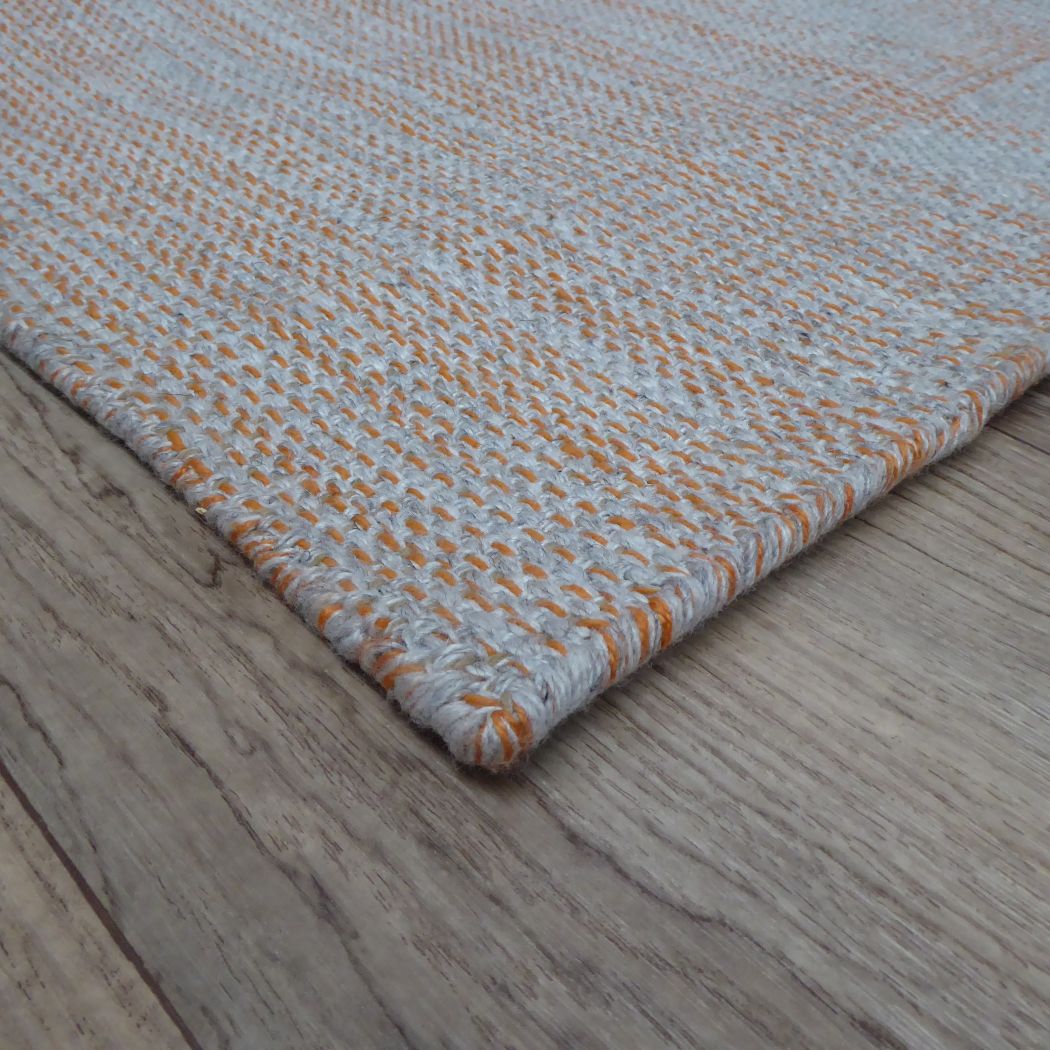 Détail du tapis gris et orange – angle du tapis montrant la bordure, la finesse du tissage et les nuances de couleurs