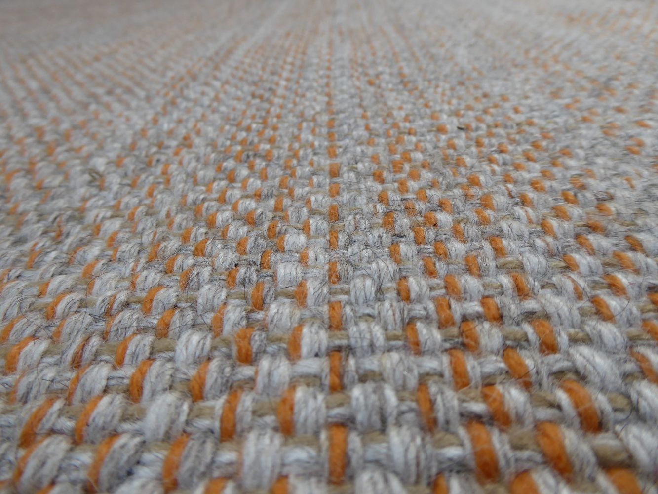 Gros plan sur le tapis gris et orange tissé main – en laine et viscose, détails du tissage artisanal et éclat des fibres