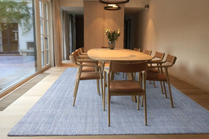 Tapis gris et bleu tissé main en laine et viscose, intégré dans une salle à manger élégante au style contemporain