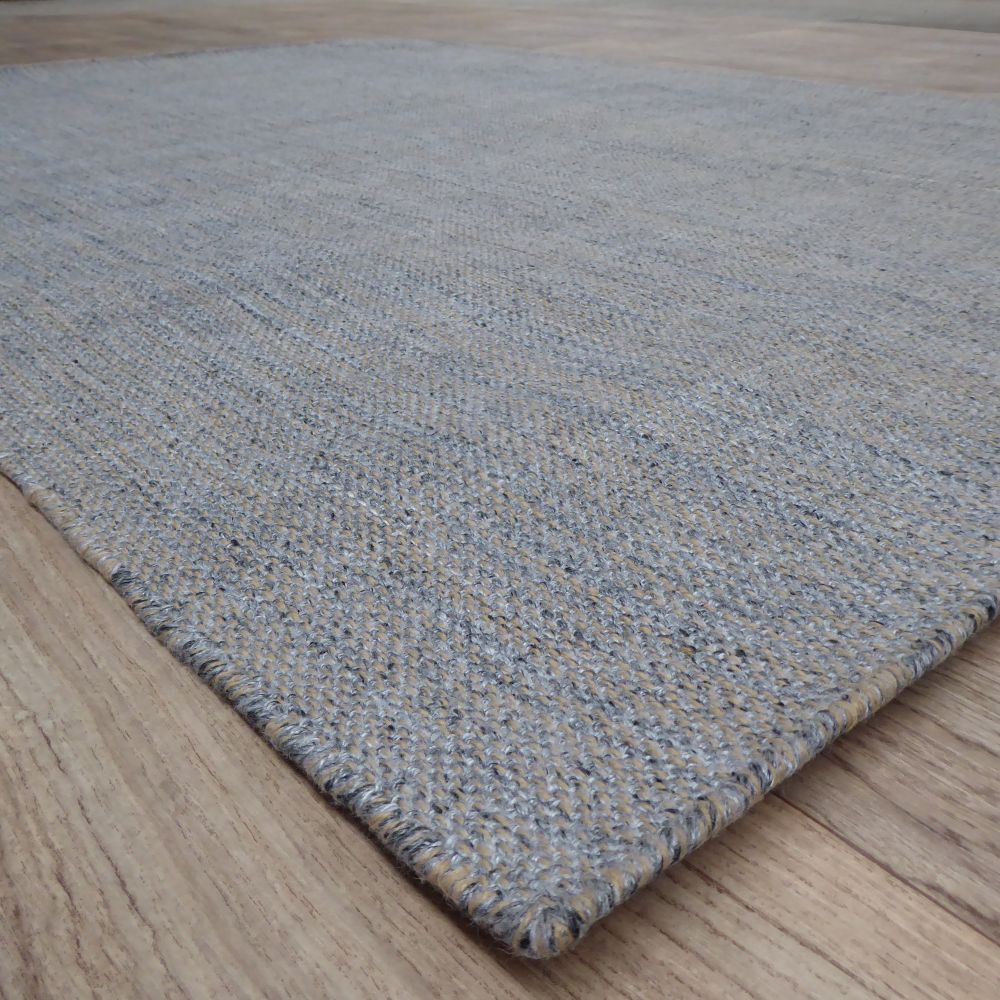 Vue en angle du tapis gris et beige tissé main, soulignant les détails du tissage artisanal et les nuances de couleurs