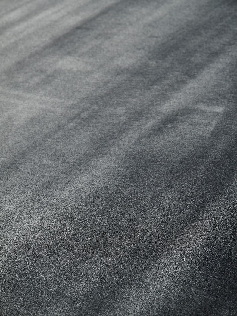 Gros plan sur les fibres brillantes d’un tapis gris soyeux en viscose