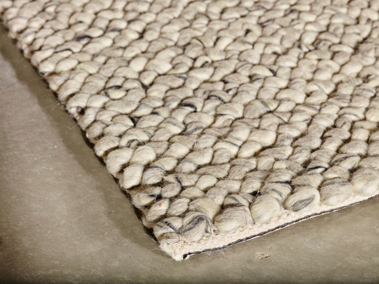 Tapis en laine ivoire et gris vu en angle, montrant l’épaisseur et le relief des boucles feutrées