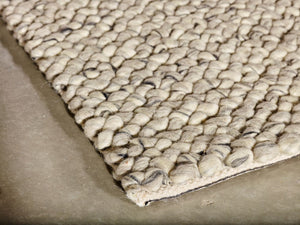 Tapis en laine ivoire et gris vu en angle, montrant l’épaisseur et le relief des boucles feutrées