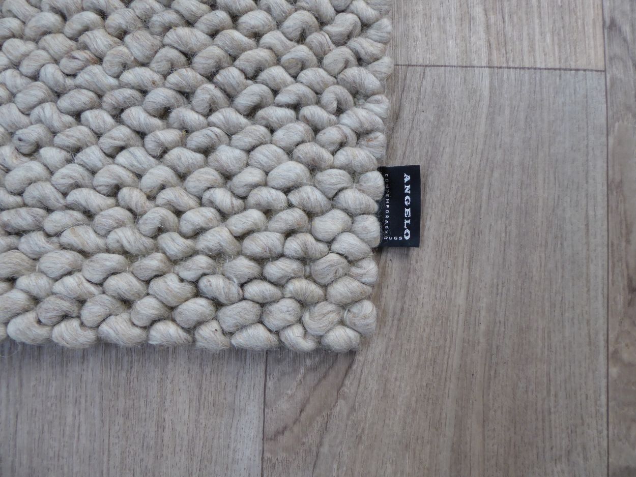 Tapis en laine bouclée beige blanc, design texturé en relief, atmosphère cosy – vue en angle