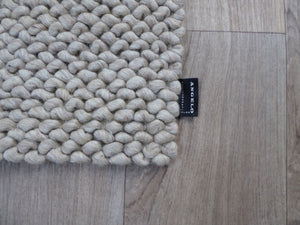 Tapis en laine bouclée beige blanc, design texturé en relief, atmosphère cosy – vue en angle