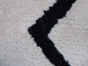 Gros plan sur la texture douce en laine du tapis ivoire et le motif noir fin