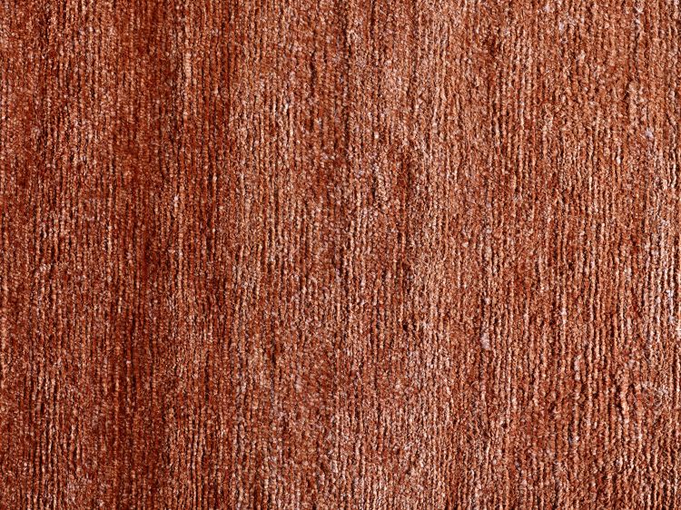 Gros plan sur la texture soyeuse du tapis en soie de bambou terracotta, soulignant finesse, douceur et brillance subtile