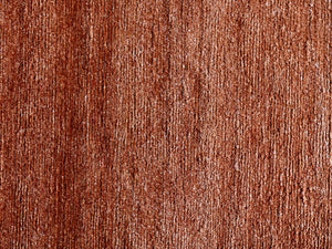 Gros plan sur la texture soyeuse du tapis en soie de bambou terracotta, soulignant finesse, douceur et brillance subtile