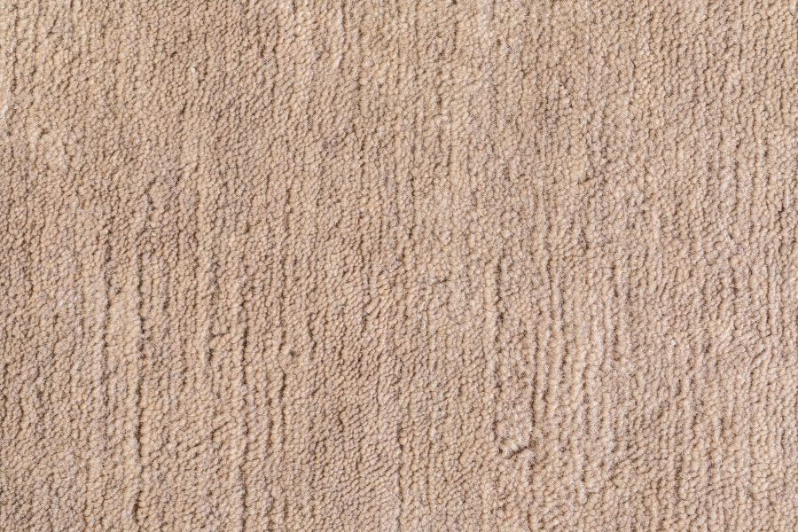 Gros plan sur le tapis sable tissé main – détail du tissage en laine douce et des fibres soyeuses