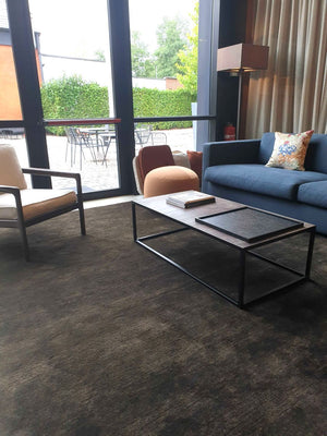 Tapis brun gris foncé en laine tissé main, intégré dans un salon contemporain, apportant chaleur et élégance à la pièce