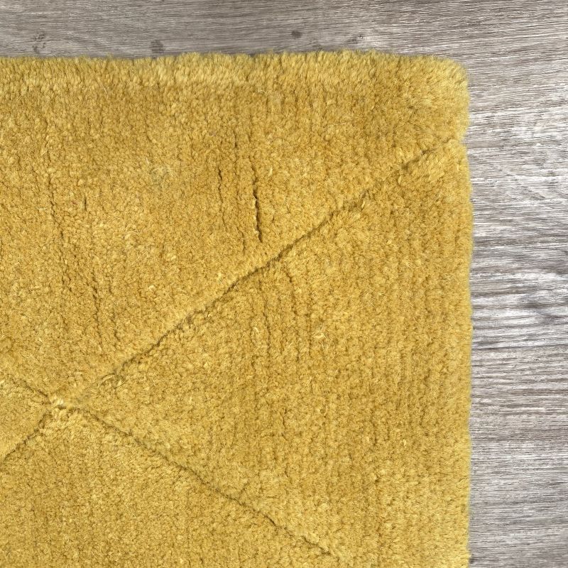 Petit tapis jaune à forme géométrique vu en perspective, montrant la texture moelleuse de la laine