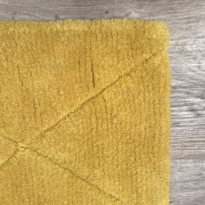 Petit tapis jaune à forme géométrique vu en perspective, montrant la texture moelleuse de la laine