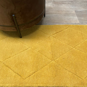 Petit tapis jaune géométrique en laine placé sous un siège design, pour une ambiance chaleureuse et moderne