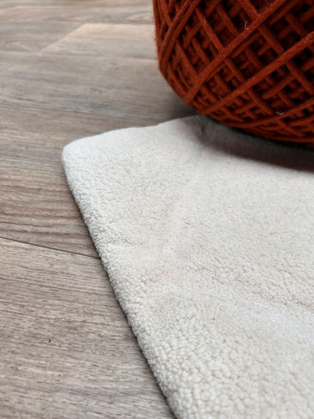 Vue en angle du tapis blanc à motifs géométriques en relief, en laine, montrant sa texture et ses finitions