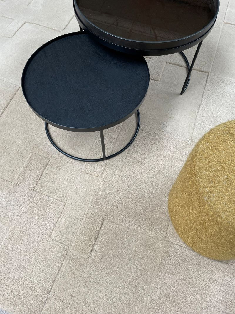 Tapis blanc cassé à motifs géométriques en relief, harmonisé avec un mobilier moderne et épuré