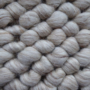 Zoom sur la texture bouclée en laine feutrée du tapis beige blanc, relief unique et toucher doux