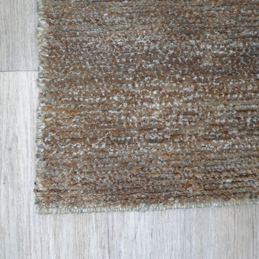 Tapis marron et blanc en soie de bambou et jute vu en angle, mettant en valeur texture et relief