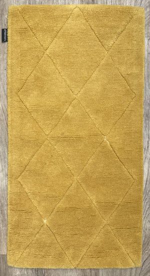 Petit tapis jaune doux en laine motif losange vu de face, posé sur un sol clair