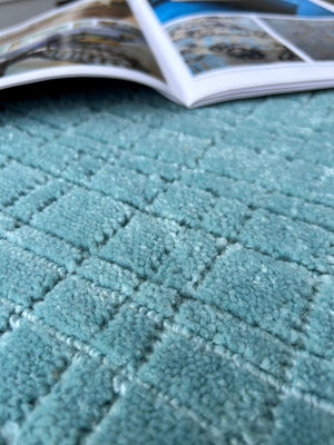 Gros plan sur la texture du tapis bleu en PET recyclé, montrant le tissage artisanal et le motif subtil à carreaux