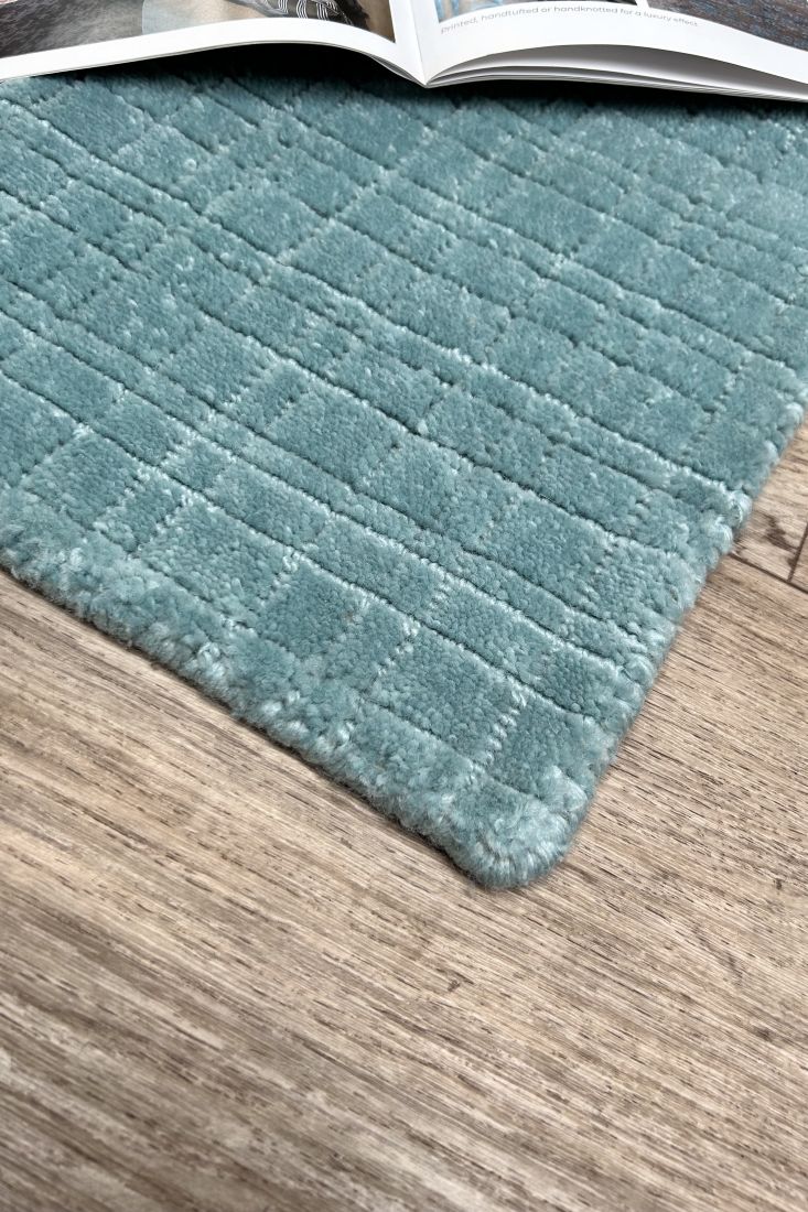 Tapis bleu durable tissé à la main en PET recyclé, motif carreaux visible depuis un angle en coin